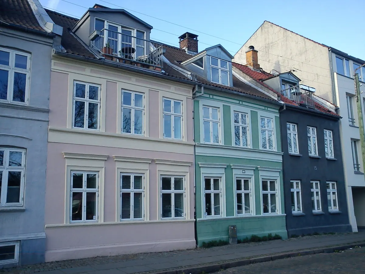 Sammenbyggede byhuse i rosa, grøn og mørkeblå med kviste i taget