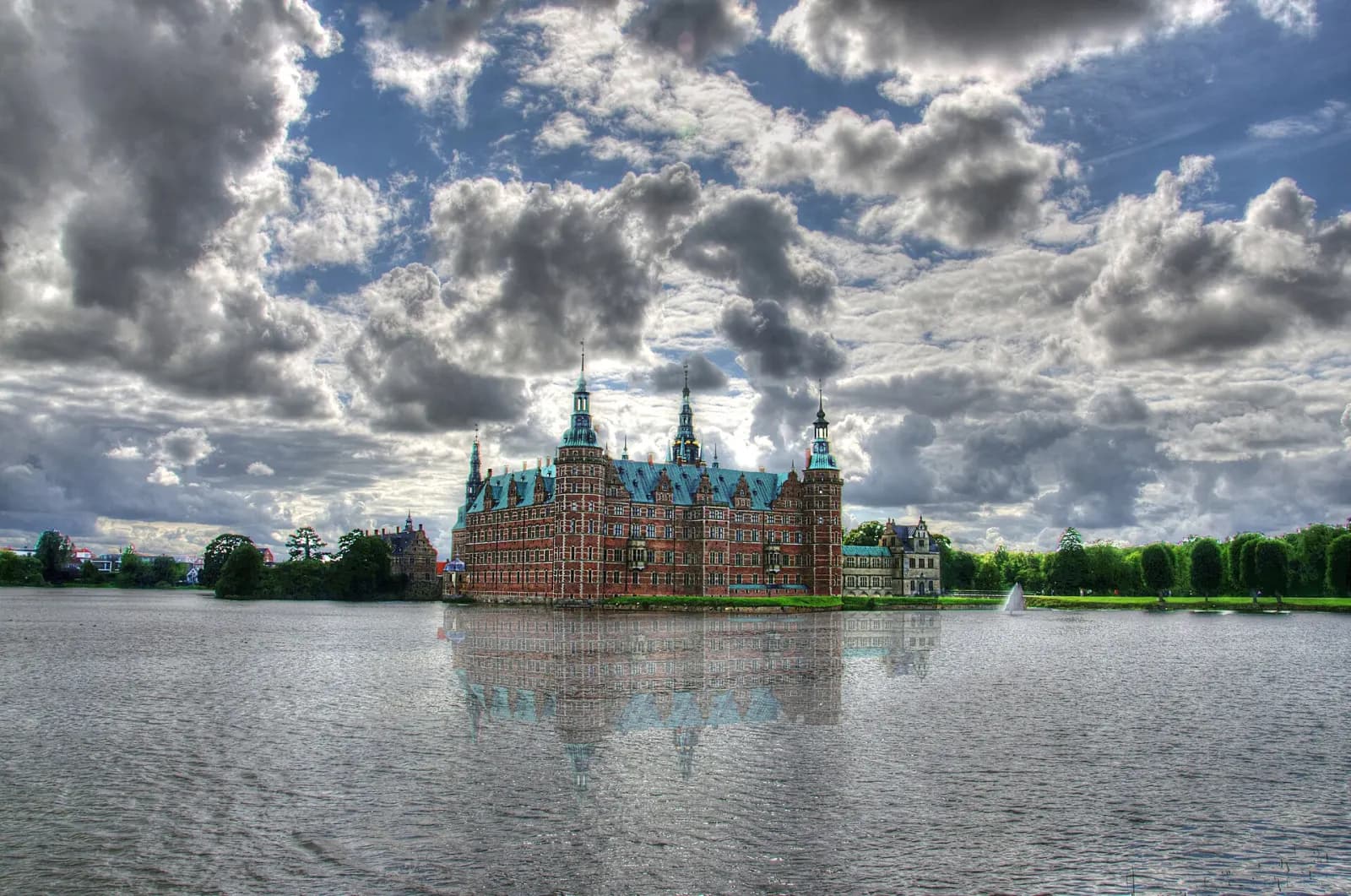 Frederiksborg Slot spejlet i slotssøen under en sky-fyldt himmel
