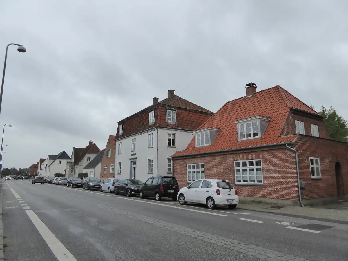Hvide og røde villaer på en villavej med parkerede biler