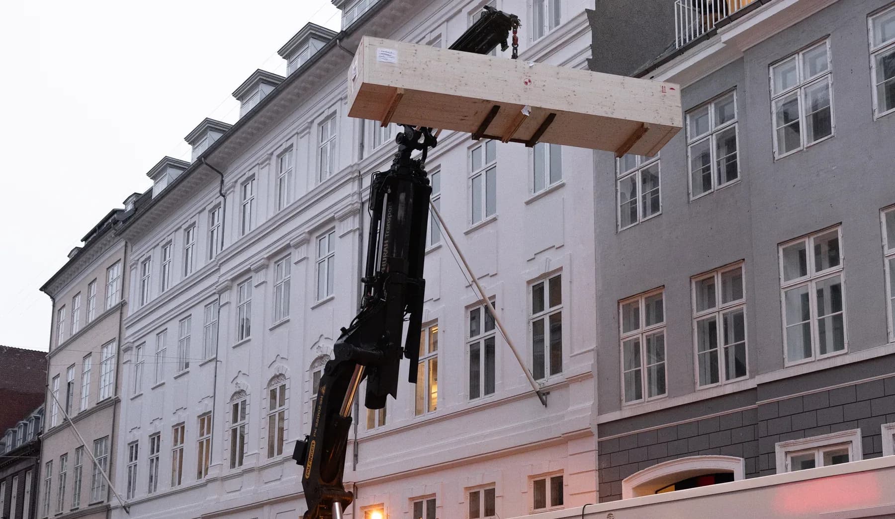 Planker løftes ind med kran i en københavnsk gade